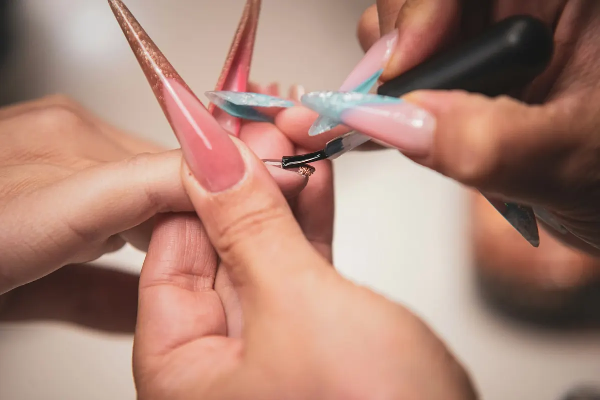 Prothésiste qui pose du vernis sur de longs ongles