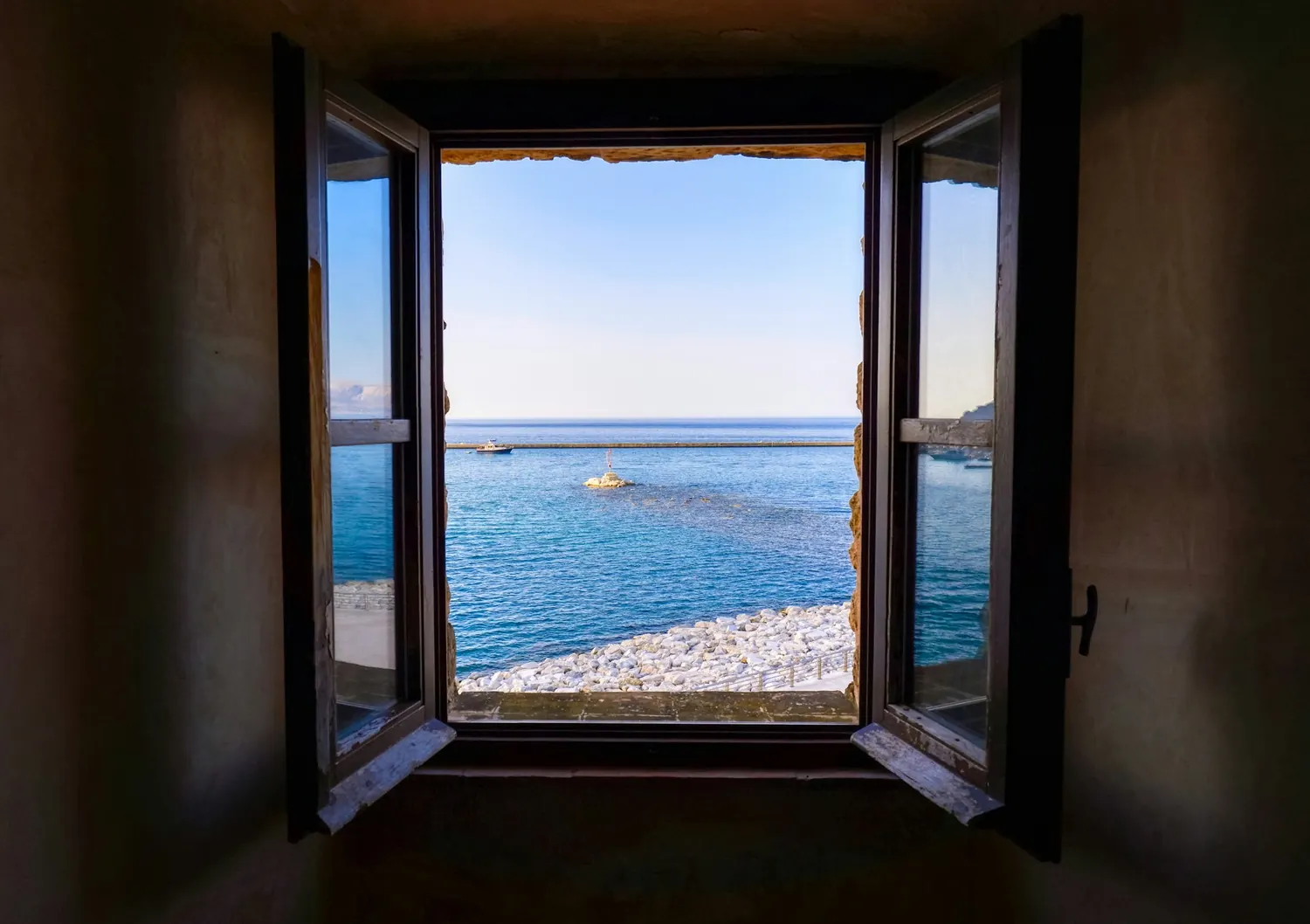 Fenêtre ouverte sur la mer et une plage de galets