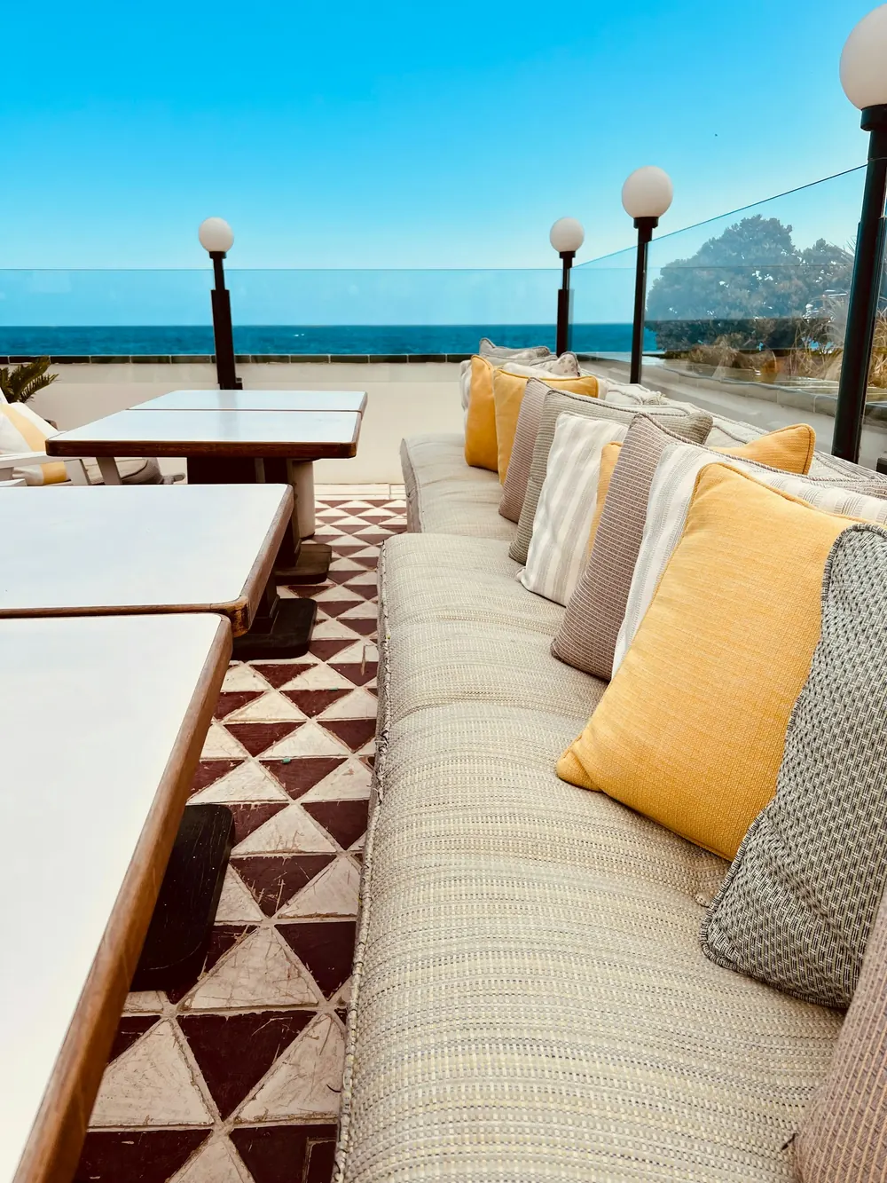 Terrasse face à la mer, coussins jaunes et carrelage à motifs